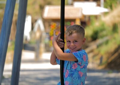 Niño divirtiéndose en los columpios del parque infantil de la tirolina.
